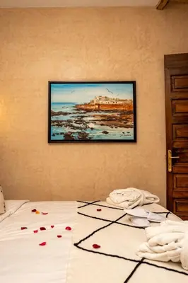 a bed with a painting hanging on a wall at Riad EL Mouloudi in Marrakech