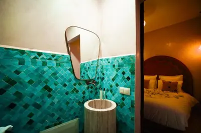 a blue tiled bathroom with a bed and a mirror at Riad EL Mouloudi in Marrakech