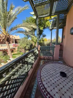 a balcony with a table and palm trees at Oasis Garden Apartment Marrakech in Marrakech