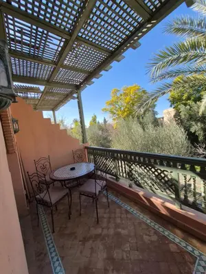 a patio with a table and chairs on a balcony at Oasis Garden Apartment Marrakech in Marrakech