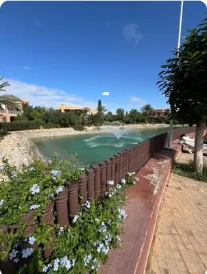a retaining wall next to a body of water with flowers at Oasis Garden Apartment Marrakech in Marrakech