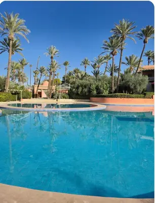 a large swimming pool with palm trees in the background at Oasis Garden Apartment Marrakech in Marrakech