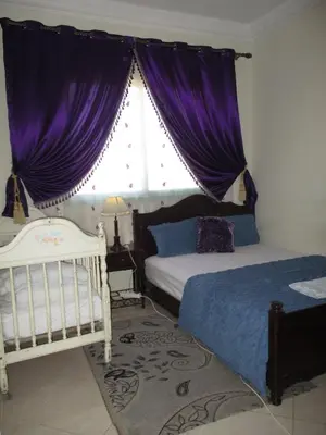 a bedroom with two beds and a window with purple curtains at Joli spacieux apparrement in Marrakech