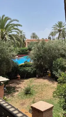a view of a resort with a pool and palm trees at Chic Palm Grove Apartment Pool View in Marrakech