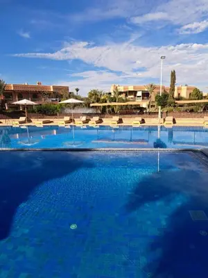 a large pool with blue water in a resort at Chic Palm Grove Apartment Pool View in Marrakech