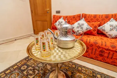 a table with glasses and a tea pot on it in front of a couch at Appart 2Ch Centre Marrakech in Marrakech