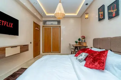 a bedroom with a white bed with red pillows on it at Appart 2Ch Centre Marrakech in Marrakech