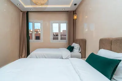 a bedroom with two beds and two windows at Appart 2Ch Centre Marrakech in Marrakech