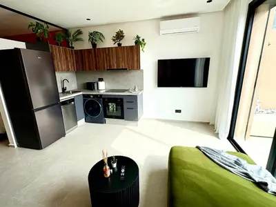 a room with a kitchen and a living room with a couch at Lovely condo Marrakech city center terrasse garage in Marrakech