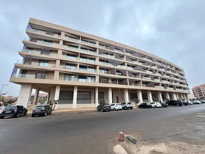 a large building with cars parked in a parking lot at Lovely condo Marrakech city center terrasse garage in Marrakech