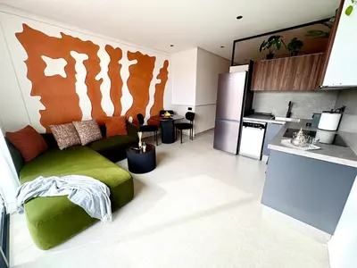 a living room with a green couch and a kitchen at Lovely condo Marrakech city center terrasse garage in Marrakech