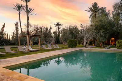 a swimming pool in a yard with palm trees at Bab Akoul Palmeraie - Boutique Hotel & Spa in Marrakech