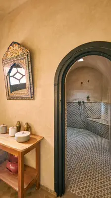 a bathroom with a table and a mirror on the wall at Bab Akoul Palmeraie - Boutique Hotel & Spa in Marrakech