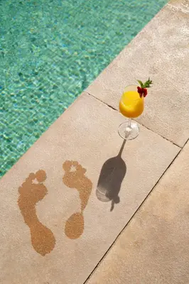 a drink sitting on a towel next to a swimming pool at Bab Akoul Palmeraie - Boutique Hotel & Spa in Marrakech
