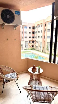 a balcony with two chairs and a table and a pool at Cozy luxury apartment downtown pool wifi fiber parking in Marrakech