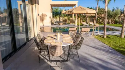 a patio with a table and chairs and a pool at Berber Garden in Aït Amara