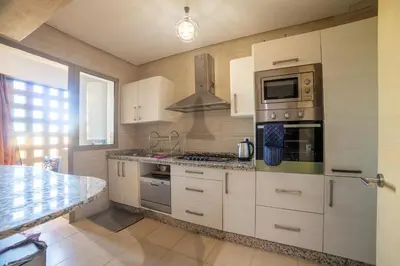 a kitchen with white cabinets and a stove top oven at Prestigia golf city marrakech in Marrakech