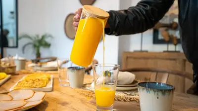 a person pouring orange juice into a glass on a table at Manzil Fanny Private Riad & Spa in Marrakech