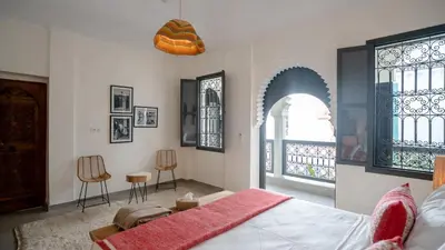 a bedroom with a bed and two chairs and a window at Manzil Fanny Private Riad & Spa in Marrakech