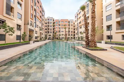 a swimming pool in the middle of a building with palm trees at Appartement Neuf et luxueux de 3 chambres proche du centre ville in Marrakech
