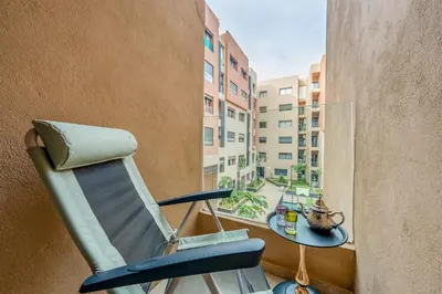 a chair sitting on a balcony with a view of a building at Appartement Neuf et luxueux de 3 chambres proche du centre ville in Marrakech