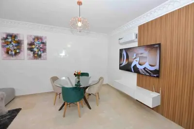 a dining room with a table and a tv on a wall at Appartement Haut Standing Hivernage, Piscine, Centre Marrakech in Marrakech
