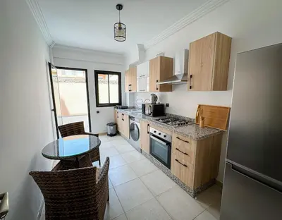 a kitchen with a table and a stove top oven at Well equipped luxury apartment in centre marrakech ctm aeroport train medina in Marrakech