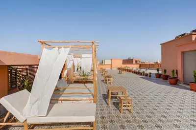 a balcony with a bed and chairs on a roof at Appartement Deluxe 2 chambres GUELIZ, Piscines, Spa, Gym in Marrakech