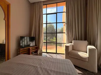 a bedroom with a bed and a chair and a television at Palais Meryem in Marrakech
