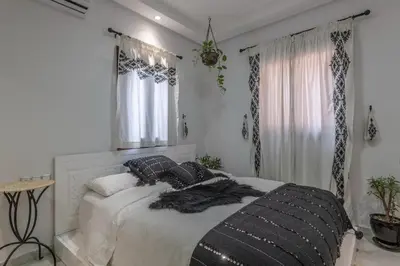 a white bedroom with a bed with black pillows at Dar Choway Ground Floor Apartment in Marrakech