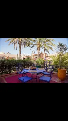 a patio with a table and chairs and palm trees at RIAD SYMPA dans residence in Marrakech