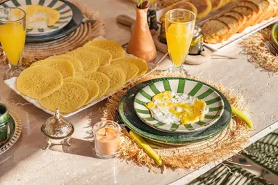 a table topped with plates of food and orange juice at Riad Exotika a Oasis with Pool, 7 min to Jemaa El Fna in Marrakech