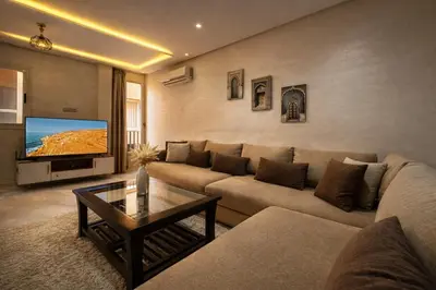 a living room with a couch and a flat screen tv at Studio Chic & Haut Standing - Parking Gratuit in Marrakech