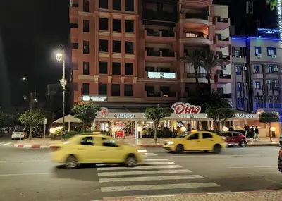 two yellow cars driving down a city street at night at Élégance et Confort au Centre de Marrakech - Hivernage in Marrakech