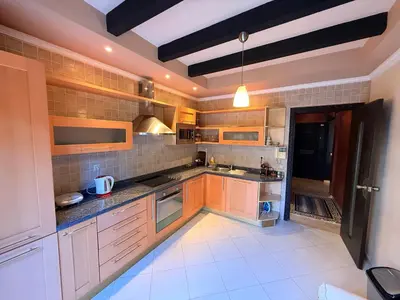 a large kitchen with wooden cabinets and a black refrigerator at Gueliz 2 BR Duplex - Terrace - Wi-Fi - Train station in Marrakech