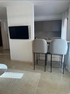 a kitchen with a table with two chairs and a television at Luxury Noria Apartment - Pool - Security - airport in Oulad Akkou