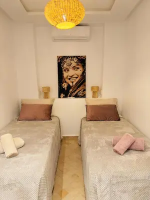 two beds in a room with a painting on the wall at Riad Marhaba in Marrakech