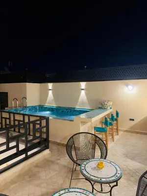a swimming pool at night with chairs and a table at Riad Marhaba in Marrakech