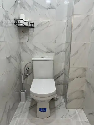 a white toilet in a bathroom with marble walls at Chic appartement Marrakech in Marrakech