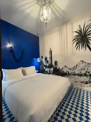 a bedroom with a large bed with a blue wall at Riad TILÉLI in Marrakech