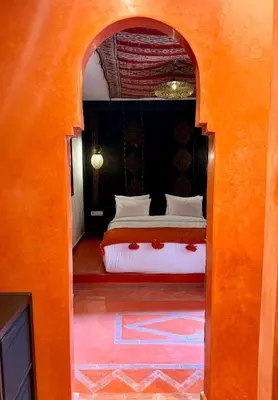 a bedroom with a bed with an orange archway at Riad TILÉLI in Marrakech