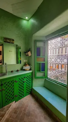 a green kitchen with a window and a bench at Riad ELJazouli in Marrakech