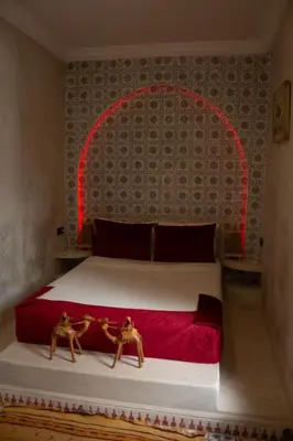 a bedroom with a large bed with a red headboard at Riad ELJazouli in Marrakech