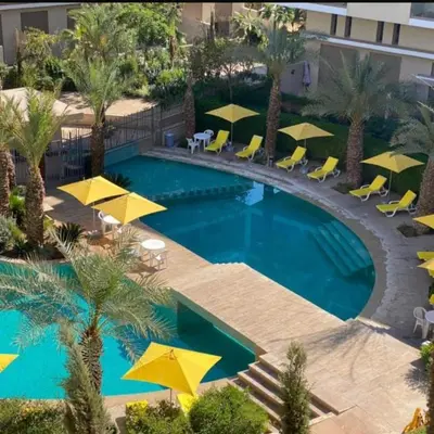 an overhead view of a swimming pool with yellow umbrellas at Modern apartment with pool view, Kech in Marrakech