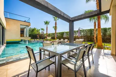 an outdoor patio with a glass table and chairs next to a swimming pool at Palais Mahora in Marrakech