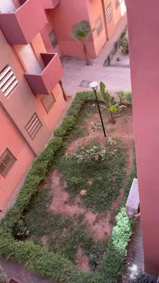 a garden in the side of a pink building at Apartment near Mènera gardens and city center in Marrakech