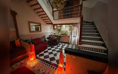 a living room with a staircase and a dining room at Riad Marrakech Red Ruby in Marrakech