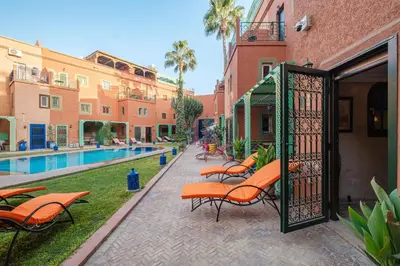 a patio with orange chairs and a gate next to a pool at Riad Marrakech Red Ruby in Marrakech