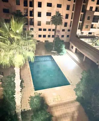 an overhead view of a pool with palm trees and a building at Appartement Moderne à Guéliz in Marrakech