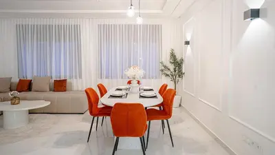 a dining room with a table and orange chairs at Appartement Moderne à Guéliz in Marrakech